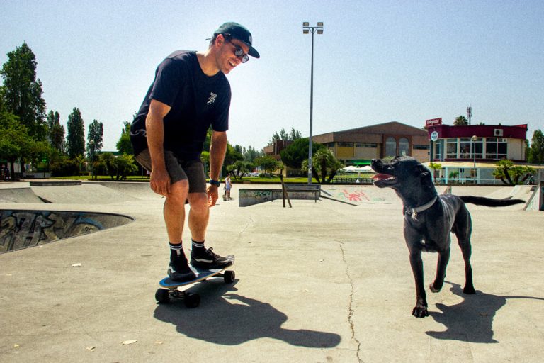Craig and his dog smiling at each other while Craig is on the Curfboard Fish and Pirata is running along